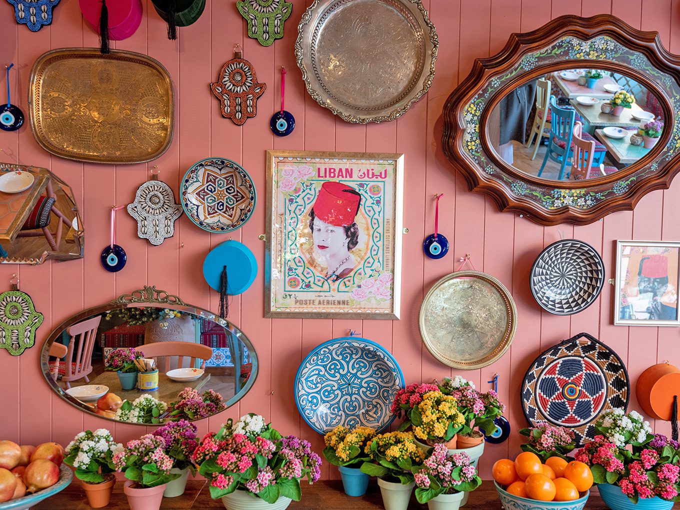pink wall with decorative plates and lebanese posters